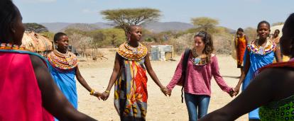 A Projects Abroad participant makes a circle with Samuru tribeswomen in Kenya. traveller holds hands with a Samuru tribe member as part of her Discovery Tour in Kenya.